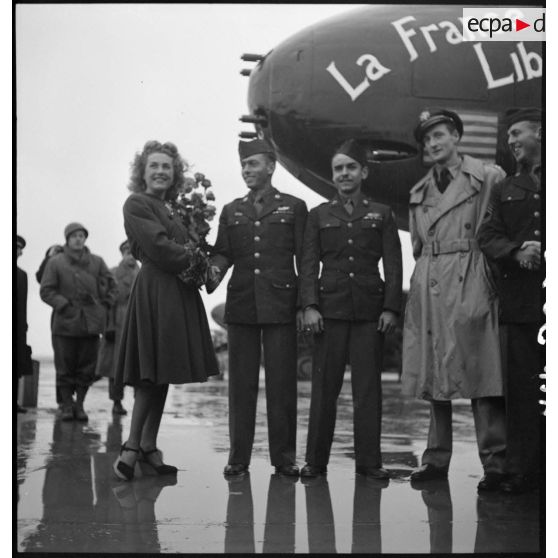 Monique Rolland sert la main d'un caporal chef américain lors de la cérémonie officielle du baptême de l'avion "France Libre" le 25 octobre 1944, au Bourget.