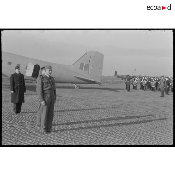 Le général  Arthur Tedder, après être descendu de l'avion, se met au garde à vous pendant l'éxécution des hymnes nationaux.