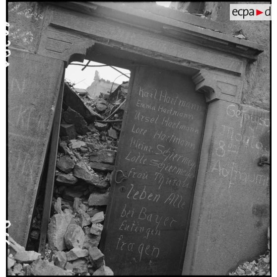 Liste de noms de rescapés inscrits sur une porte dans Pforzheim en ruine.