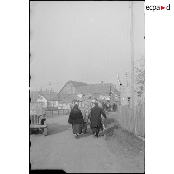 Habitants de la ville de Rhinau (Bas-Rhin) fuyant leur ville bombardée par des tirs de mortiers allemands le 27 décembre 1944. [description provisoire]