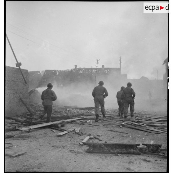 Rhinau (Bas-Rhin) est en proie aux flammes et en ruine, le village alsacien ayant été bombardé par les Allemands entre le 10 et le 22 décembre 1944. Les troupes patrouillent dans la commune dévastée. [description provisoire]