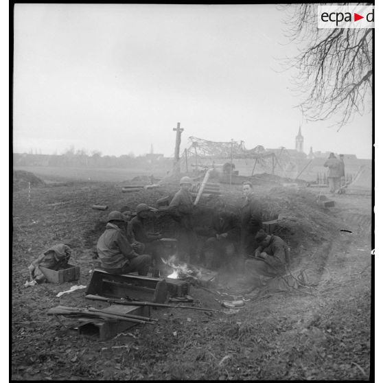 Artilleurs du 1er groupe du 3e RAC (Régiment d'artillerie coloniale) se réchauffant à l'emplacement de leur pièce d'artillerie près de Limersheim (Bas-Rhin). [description provisoire]