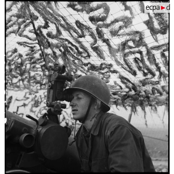 Un artilleur du 1er groupe du 3e RAC (Régiment d'artillerie coloniale) sert un canon de 155 mm Gun implanté près de Limersheim (Bas-Rhin) : pointeur, il effectue les réglages pour l'exécution du tir sur les positions allemandes. [description provisoire]