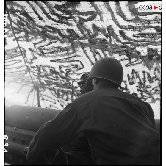 Un artilleur du 1er groupe du 3e RAC (Régiment d'artillerie coloniale) sert un canon de 155 mm Gun implanté près de Limersheim (Bas-Rhin) : pointeur, il effectue les réglages pour l'exécution du tir sur les positions allemandes. [description provisoire]