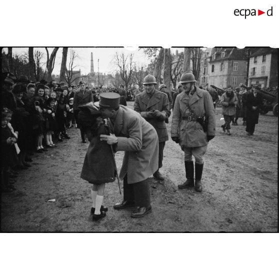 Le général de Lattre de Tassigny, à la tête de la 1re armée, embrasse une fillette lors d'une revue de la brigade Fabien, à Vesoul, le 10 décembre 1944. Derrière le général, le colonel Fabien. [description provisoire]