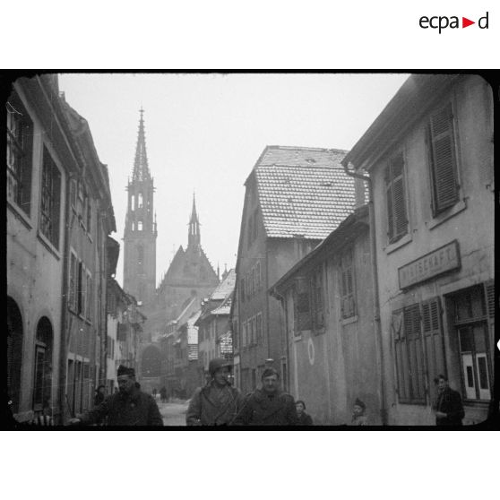 Thann (Haut-Rhin) : vue d'une rue avec l'église en arrière-plan. [description provisoire]