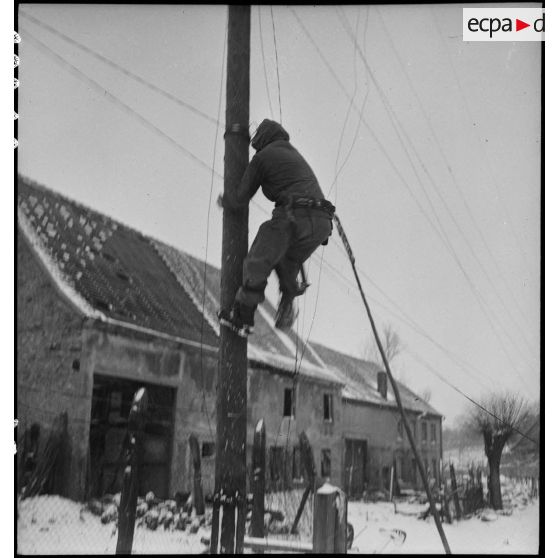 Pose de lignes téléphoniques dans un village du front dans la région de Sarreguemines (Moselle) par le génie américain. [description provisoire]