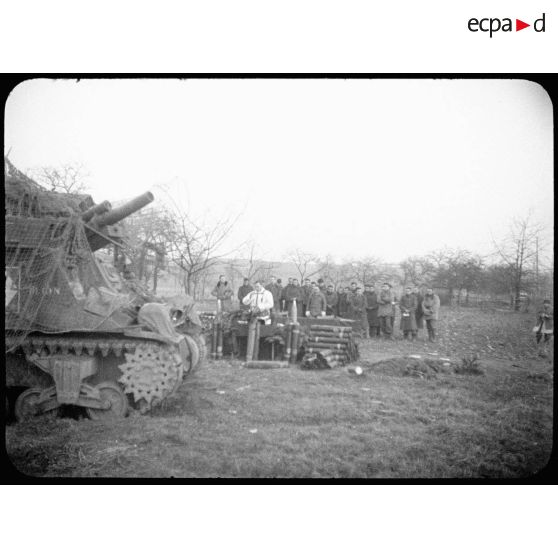 Une messe de Noël est dite en plein air par le père Etienne pour une batterie du 62e RAA (Régiment d'artillerie d'Afrique) déployée dans le Haut-Rhin. Au premier plan, le canon automoteur M7 Priest "Dijon". [description provisoire]