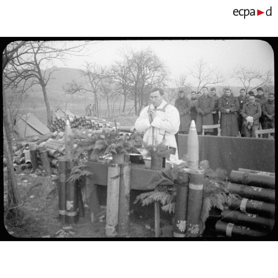 Une messe de Noël est dite en plein air par le père Etienne pour une batterie du 62e RAA (Régiment d'artillerie d'Afrique) déployée dans le Haut-Rhin. [description provisoire]