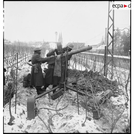 Des canonniers d'une section du 21e groupe antillais des FTA (Forces terrestres antiaériennes), qui fait partie de la 1re DMI (Division de marche d'infanterie) (ex 1re DFL), mettent en batterie une mitrailleuse lourde aux portes d'Obernai (Bas-Rhin) dont ils doivent assurer la défense. [description provisoire]