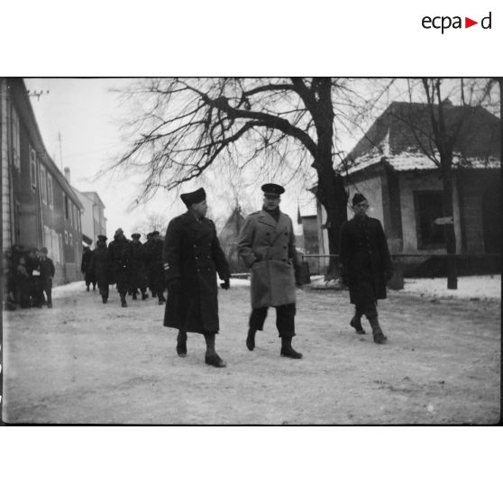 Délégation d'attachés militaires étrangers en visite sur le front d'Alsace, cornaquée par un colonel français, traversant le village de Steinbrunn-le-Bas (Haut-Rhin) où se trouve le PC la 9e DIC (Division d'infanterie coloniale). [description provisoire]