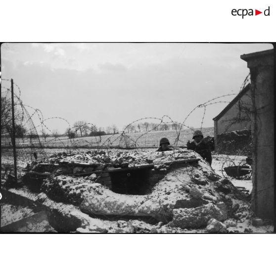 Deux sentinelles de la 9e DIC (Division d'infanterie coloniale) devant leur abri enterré et entouré de fil de fer barbelé non loin du village de Steinbrunn-le-Bas (Haut-Rhin). [description provisoire]