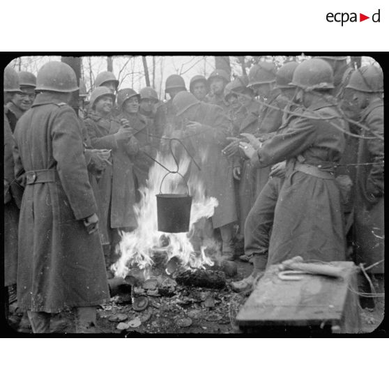 Soldats se réchauffant autour d'un feu où cuit une soupe, après un exercice de franchissement de cours d'eau non loin de Sierentz (Haut-Rhin). [description provisoire]