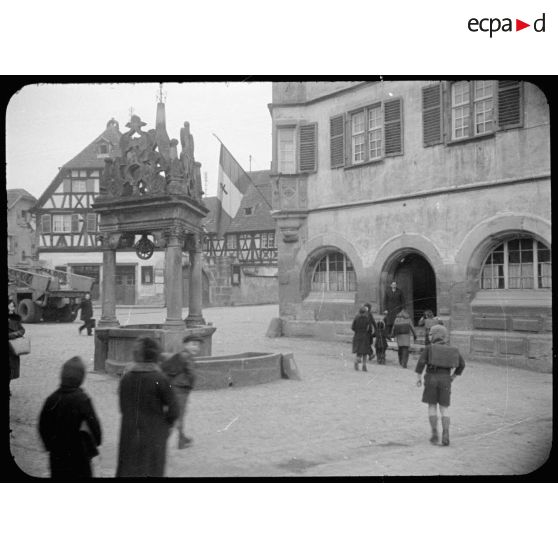 Elèves se rendant à l'école dans le village de Boersch (Bas-Rhin) sur la place du Puits à six seaux. [description provisoire]