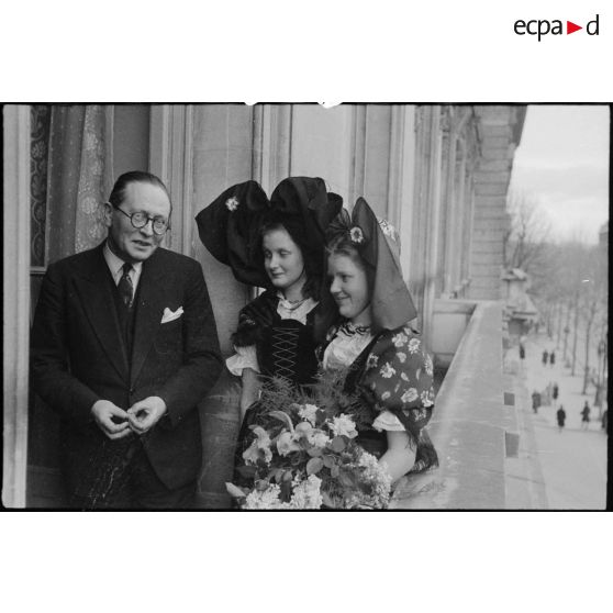 Le ministre à la Guerre, André Diethelm, reçoit deux jeunes femmes revêtues du costume traditionnel alsacien, à Paris. [description provisoire]