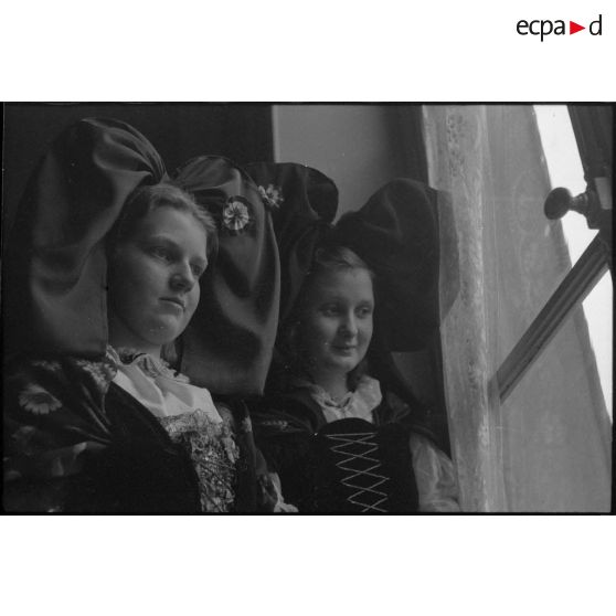 Portrait de deux jeunes femmes revêtues du costume traditionnel alsacien, reçues par le ministre à la Guerre, André Diethelm, à Paris. [description provisoire]