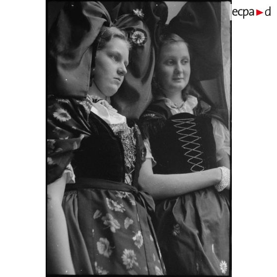 Portrait de deux jeunes femmes revêtues du costume traditionnel alsacien, reçues par le ministre à la Guerre, André Diethelm, à Paris. [description provisoire]