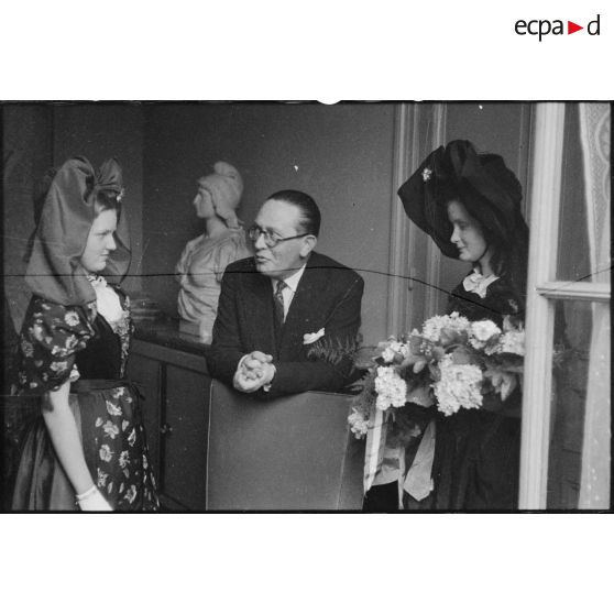 Le ministre à la Guerre, André Diethelm, reçoit deux jeunes femmes revêtues du costume traditionnel alsacien, à Paris. [description provisoire]