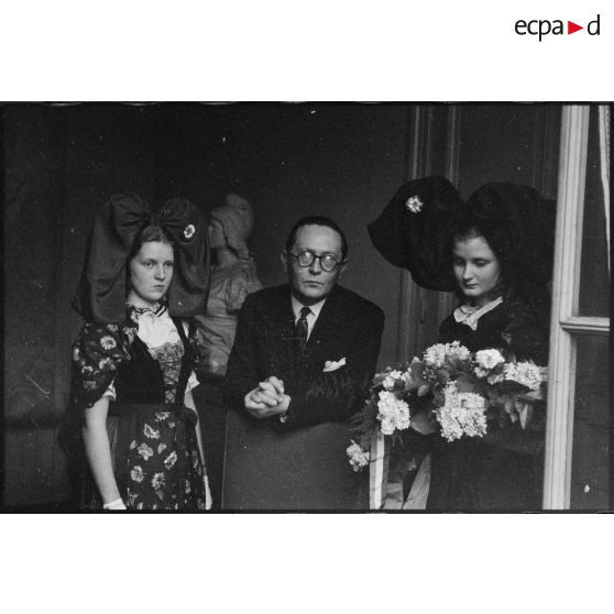 Le ministre à la Guerre, André Diethelm, reçoit deux jeunes femmes revêtues du costume traditionnel alsacien, à Paris. [description provisoire]