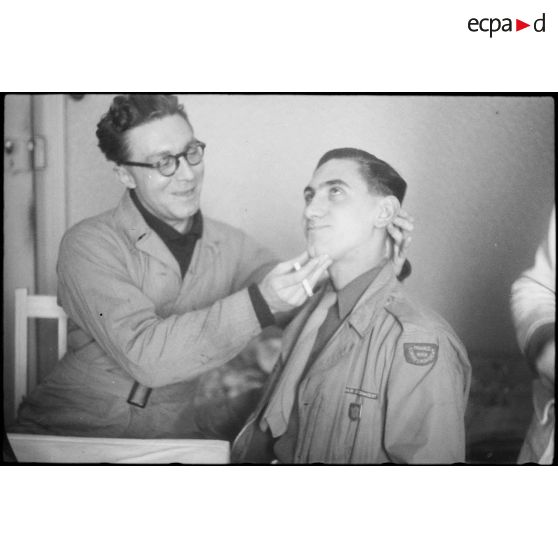 Le photographe André Gandner du Service cinématographique de l'armée (SCA) prend la pose. Il porte l'insigne métallique de la 2e division blindée (2e DB).