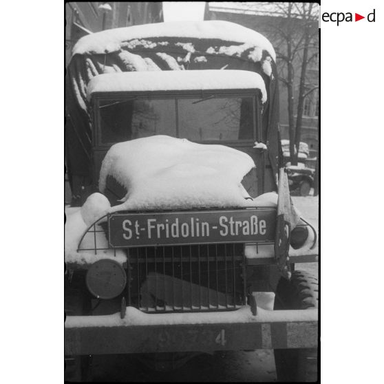 Plaque de rue allemande installée sur la calandre d'un camion GMC de la 297e compagnie du Train de la 2e division blindée (2e DB).