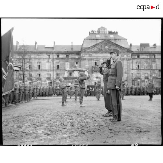 Au cours d'une cérémonie sur la place du château des Rohan à Saverne, le général de Gaulle et le lieutenant général américain Jacob Devers, commandant le 6e groupe d'armées, saluent les emblèmes.<br><br>