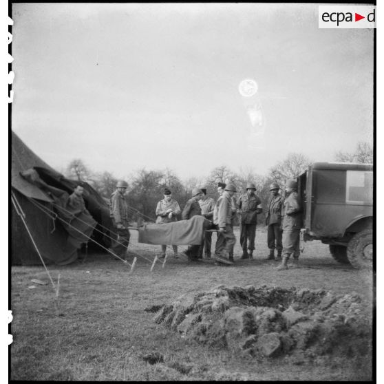 Evacuation d'un blessé d'un poste sanitaire du 13e bataillon médical (BM 13) de la 2e division blindée (2e DB). [description provisoire]