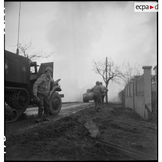 Un caméraman du SCA quittant un half-track, une caméra Bell & Howell à la main. [description provisoire]