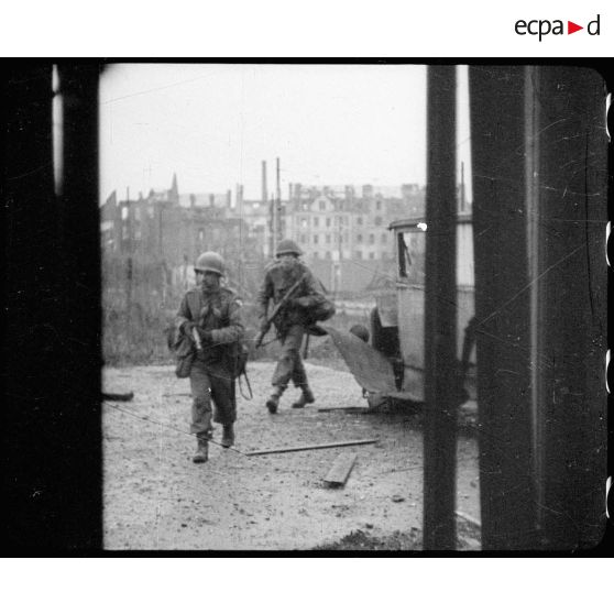 Les fantassins américains fouillent les décombres. [description provisoire]