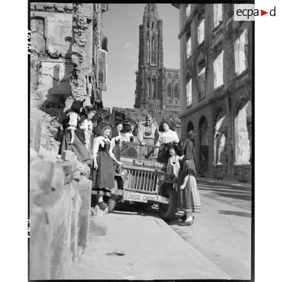 A Strasbourg, des Alsaciennes en costume entourent la jeep "Presse Cinéma" du SCA. [description provisoire]