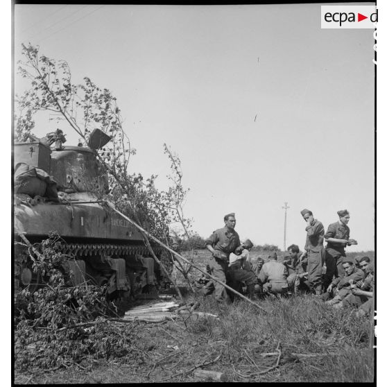 Les équipages de chars Sherman du 12e régiment de chasseurs d'Afrique (12e RCA) de la 2e division blindée (2e DB) font une pause déjeuner près de leurs blindés.<br>