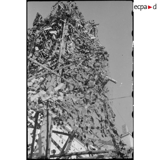 Bâtiment militaire dans Karlsruhe, entouré de poteaux camouflés en arbres qui semblent alimenter le bâtiment en électricité.