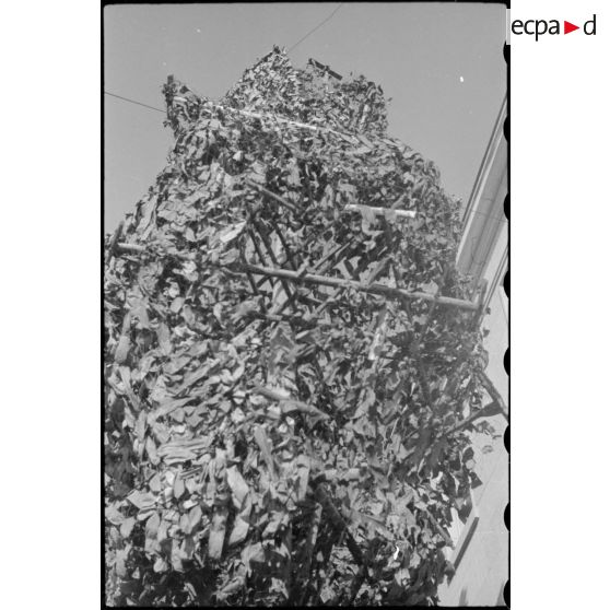 Bâtiment militaire dans Karlsruhe, entouré de poteaux camouflés en arbres qui semblent alimenter le bâtiment en électricité.