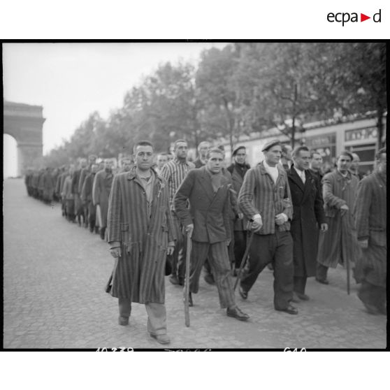 Des déportés politiques s'éloignent de l'Arc de Triomphe à l'issue d'une cérémonie de ravivage de la flamme sur la tombe du Soldat inconnu.