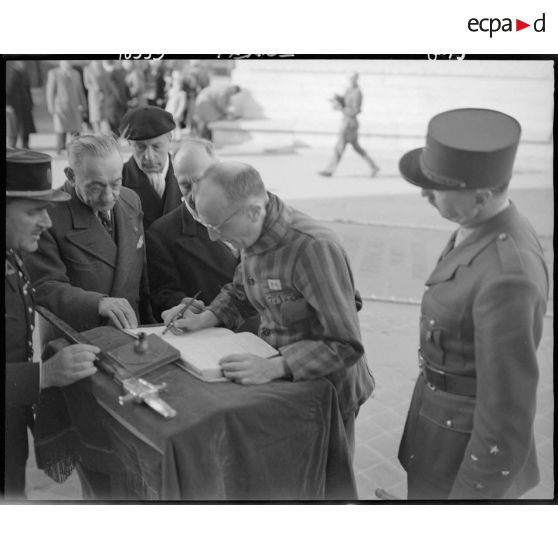Un déporté politique signe le livre d'or à l'issue d'une cérémonie de ravivage de la flamme sur la tombe du Soldat inconnu à l'Arc de Triomphe.