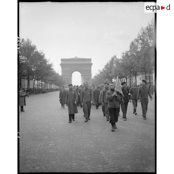 Des déportés politiques s'éloignent de l'Arc de Triomphe à l'issue d'une cérémonie de ravivage de la flamme sur la tombe du Soldat inconnu.
