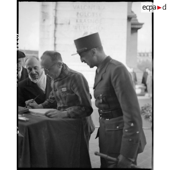 Un déporté politique signe le livre d'or à l'issue d'une cérémonie de ravivage de la flamme sur la tombe du Soldat inconnu à l'Arc de Triomphe.
