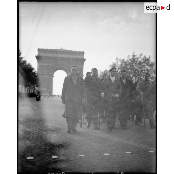 Des déportés politiques s'éloignent de l'Arc de Triomphe à l'issue d'une cérémonie de ravivage de la flamme sur la tombe du Soldat inconnu.