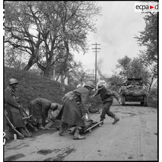Un soldat nord-africain, blessé lors d'un accrochage devant Fützen, est évacué sur un brancard par une équipe médicale et des marsouins de la 9e division d'infanterie coloniale (9e DIC).
