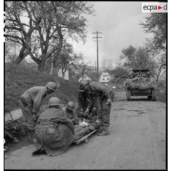 Un soldat nord-africain, blessé lors d'un accrochage devant Fützen, est évacué sur un brancard par une équipe médicale et des marsouins de la 9e division d'infanterie coloniale (9e DIC).