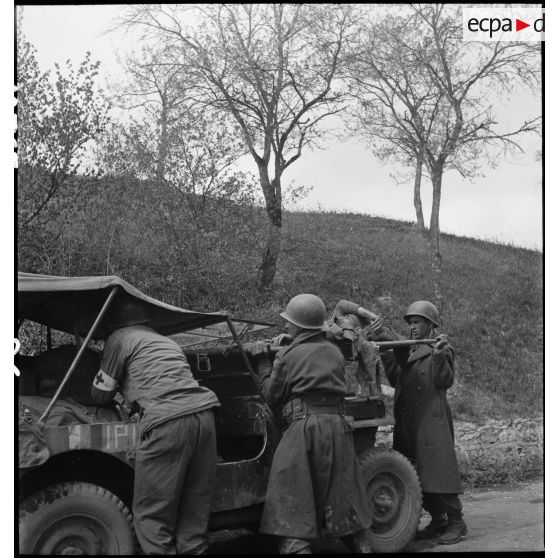 Un soldat nord-africain, blessé lors d'un accrochage devant Fützen, est installé à bord d'une jeep sanitaire par une équipe médicale et des marsouins de la 9e division d'infanterie coloniale (9e DIC).