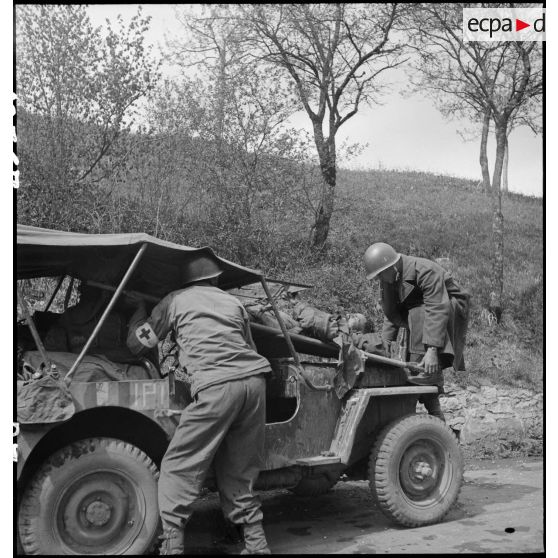 Un soldat nord-africain, blessé lors d'un accrochage devant Fützen, est installé à bord d'une jeep sanitaire par une équipe médicale et des marsouins de la 9e division d'infanterie coloniale (9e DIC).