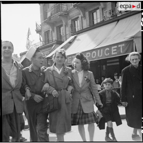Un légionnaire et des civiles déambulent dans une rue de Paris.