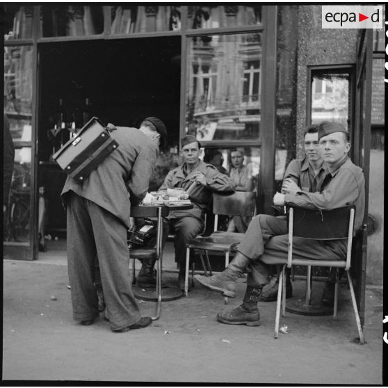 Soldats américains ou français attablés à la terrasse d'un café à Paris.