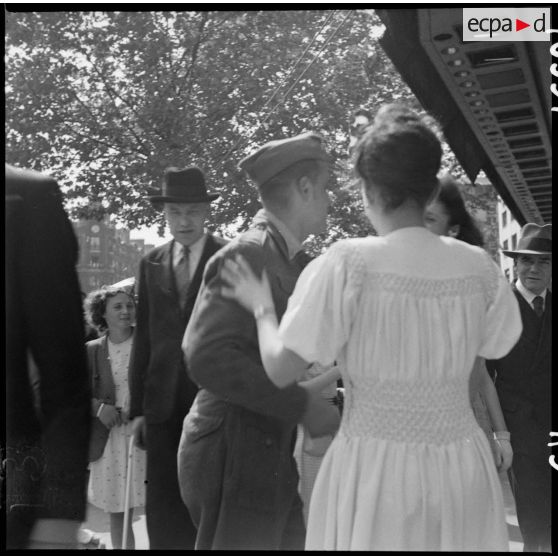 Un soldat français ou américain fraternise avec des parisiennes dans une rue de la capitale.