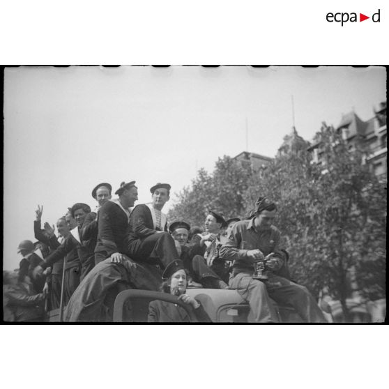 Marins français embarqués sur un véhicule circulant sur les Champs-Elysées.