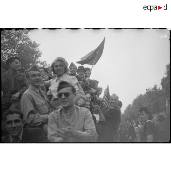 Population civile et militaires américains embarqués sur des véhicules circulant sur les Champs-Elysées.