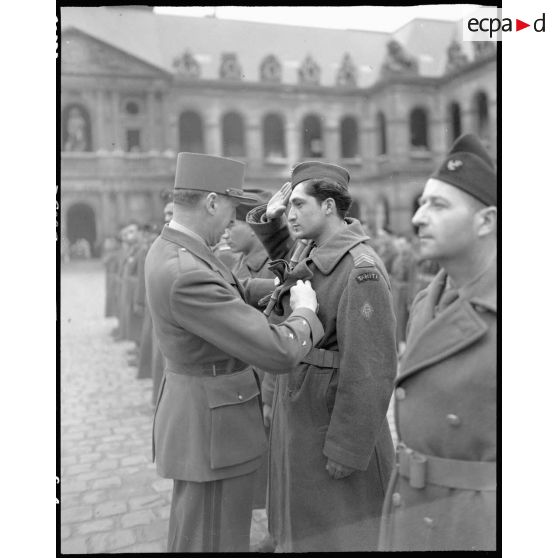 Le général Koenig décore un soldat tahitien lors d'une cérémonie dans la cour d'honneur de l'hôtel national des Invalides.