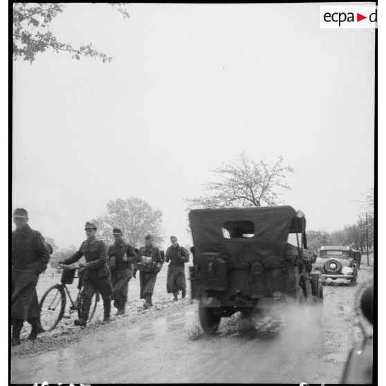 Des prisonniers de guerre allemands qui se dirigent vers des camps, croisent un convoi de l'armée américaine.