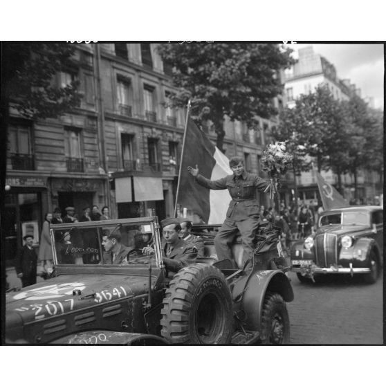 Jules Carron, millionième prisonnier français libéré rapatrié, circule dans les rues de Paris à bord d'un Dodge command car de l'armée américaine.
